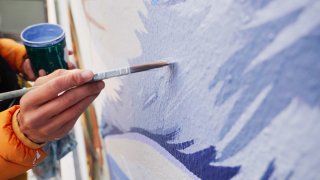 a painter with blue paint brushes it onto a wall