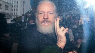 In this file photo, Julian Assange gestures to the media from a police vehicle on his arrival at Westminster Magistrates court on April 11, 2019 in London, England.