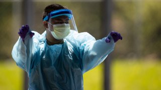 A medical professional adjusts his protective equipment as he walks through a coronavirus (covid-19) drive thru test site