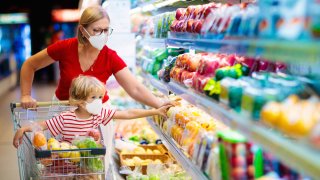 Foto de banco de imágenes que muestra a mujer y su hijo con cubrebocas en un supermercado.
