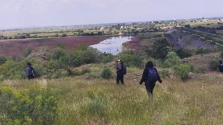 Tres personas buscan fosas clandestinas en un campo en México