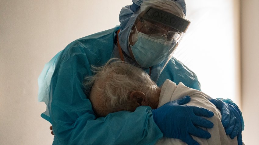 A health care worker holds an elderly coronavirus patient.