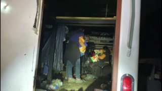 Imagen de migrantes, que están de espaldas, que viajaban hacinados en un camión
