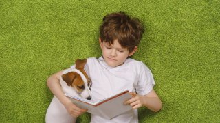 Niño leyendo libro a perro