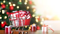 Little shopping cart full of christmas gifts on christmas tree background.