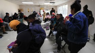 Foto de un grupo de migrantes sentados en el comedor de la catedral.