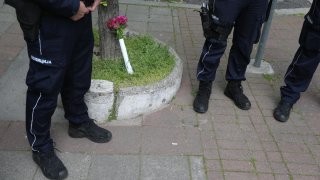 Foto de tres policías junto a un pequeño ramo de flores.