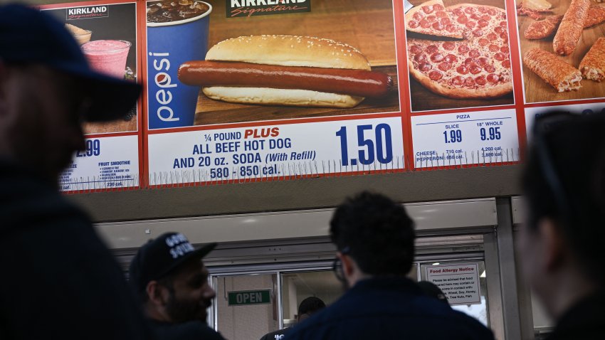 Customers wait in line to order below signage for the Costco Kirkland Signature $1.50 hot dog and soda combo in Hawthorne, California.