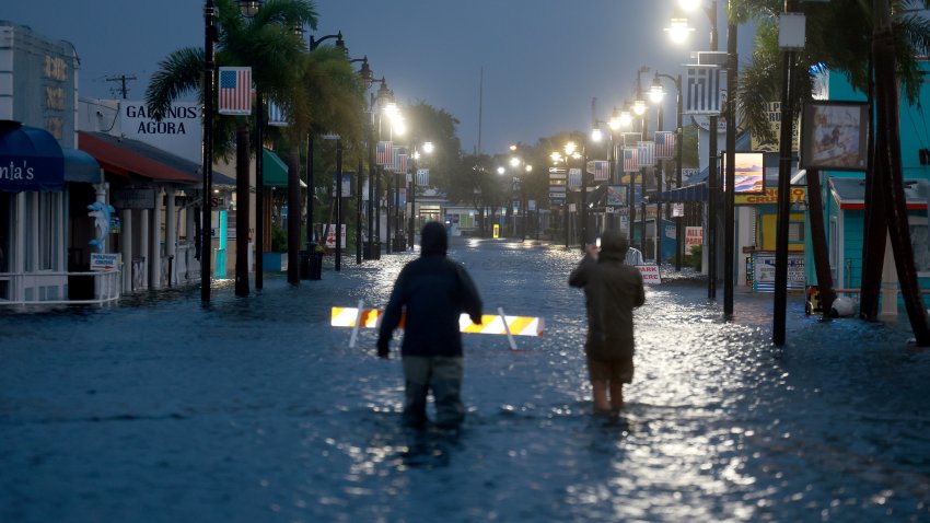 Reporters wade through flood waters as it inundates the downtown area after Hurricane Idalia passed offshore on August 30, 2023 in Tarpon Springs, Florida.