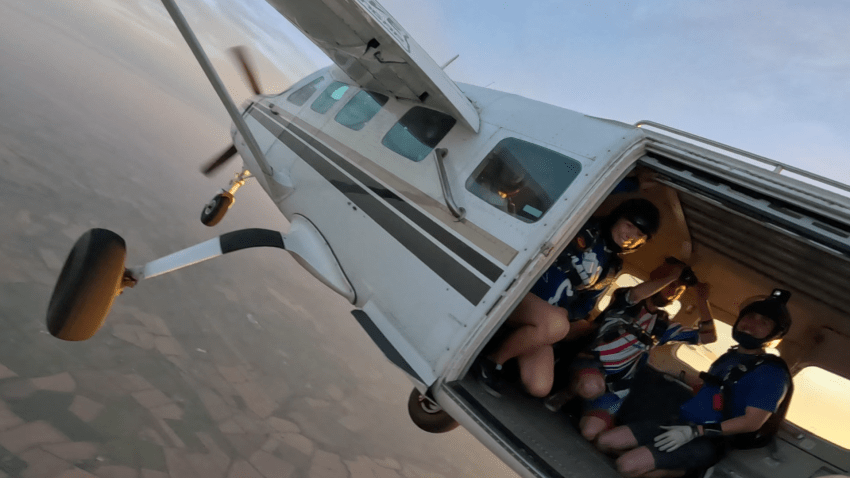 People smile from the inside of a small airplane before they skydive