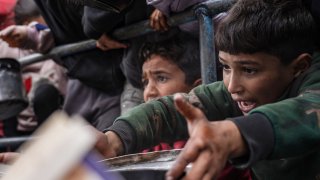 Niños palestinos aguardan este sábado por comida en Rafah, en el sur de la franja de Gaza, colmada de desplazados por la guerra.