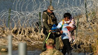 ARCHIVO - Un grupo de migrantes es detenido por oficiales en la frontera entre Texas y México el 3 de enero de 2024, en Eagle Pass, Texas.