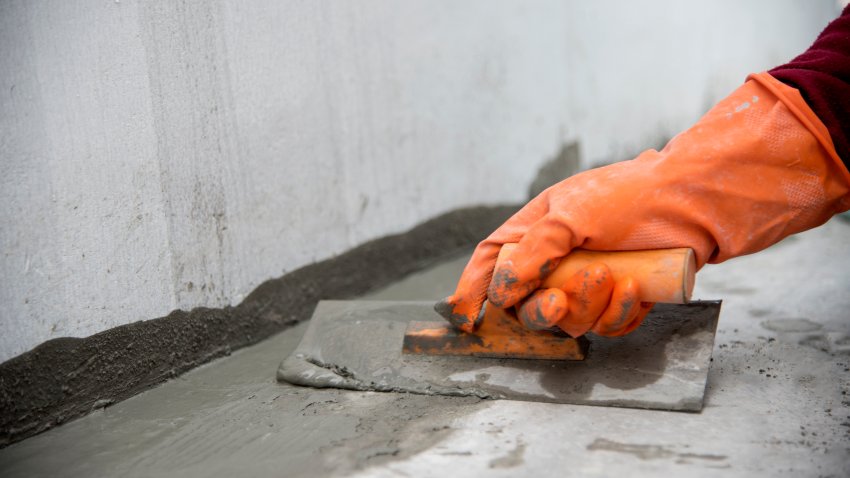close up hand labor hold trowel masonry work in construction site