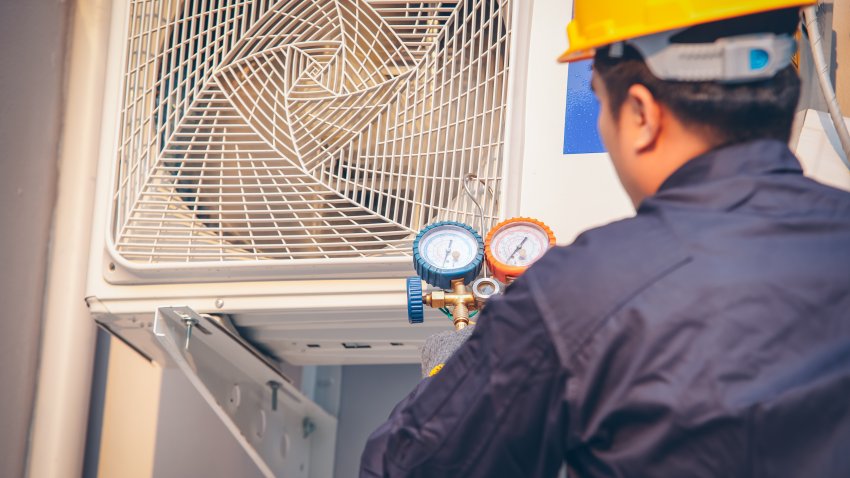 Technician vacuum pump evacuates and checking new air conditioner,Male technician repairing air conditioner outdoors.