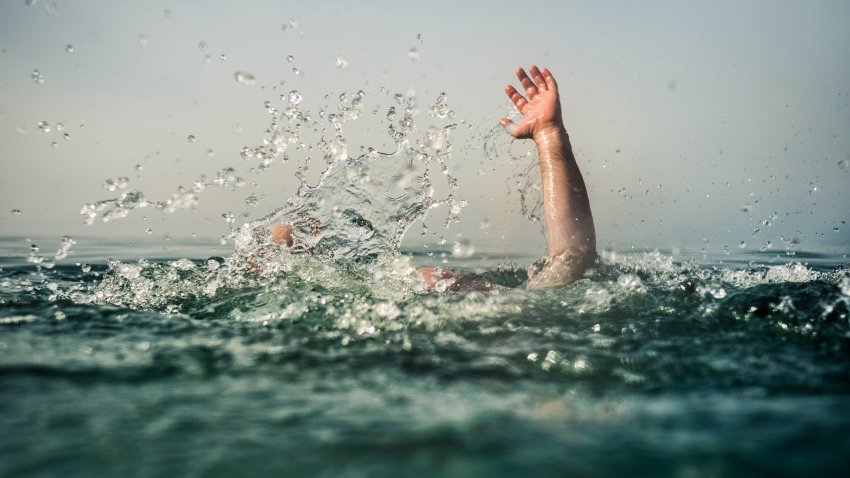 Hand reaching out of deep water, focus on water splash