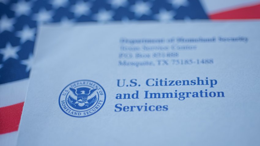 Hand touching Letter (Envelope) from USCIS on  flag of USA background. Close up view.