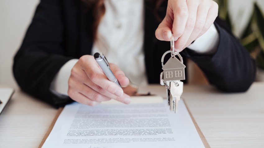 Saleswoman holding house keys and pen at office