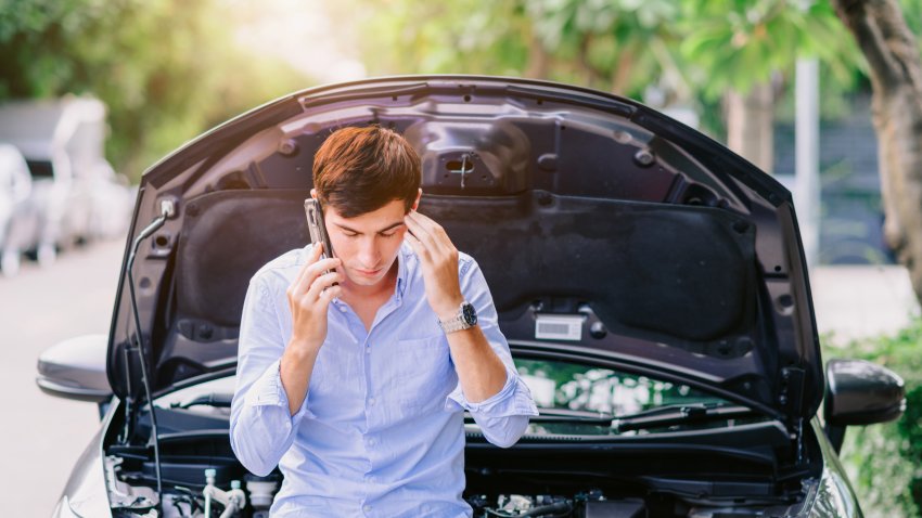 man using the phone to call an insurance company Because the car has been damaged by the engine system.