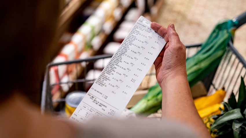 Close-up on a woman looking at a receipt after shopping at the supermarket – cost of living concepts