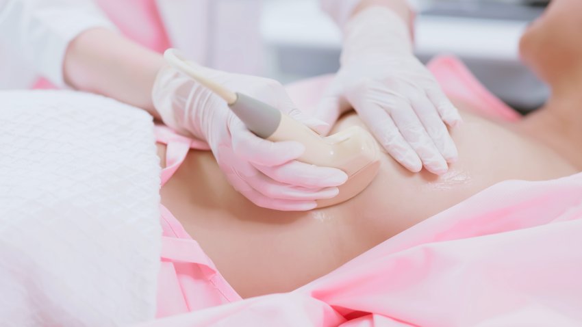 close up of asian doctor using ultrasound scanner performing examination of breast for her patient – cancer awareness feminine health medical concept