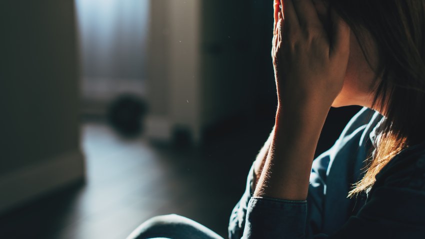 Silhouette of sad and depressed woman sitting on the floor at home