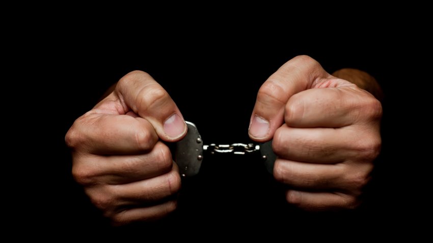 Handcuffes on man hand’s on black background