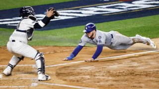 Gavin Lux (d) de los Dodgers se desliza hacia el plato y es tocado por José Trevino (i) de los Yankees durante la cuarta entrada del Juego 3 de la Serie Mundial.