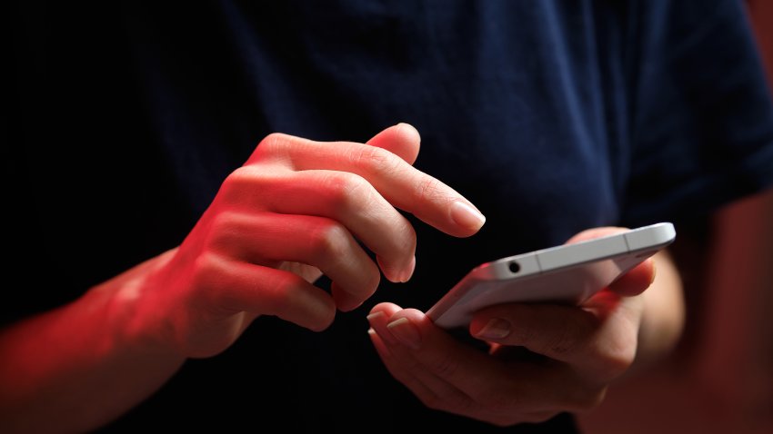 A mobile phone in the hands of a girl. A young woman in a black T-shirt is holding a phone. The fraudster sends an email message. The work of a freelancer, businessman. The wife checks messages and notifications on social networks. Wireless technologies.