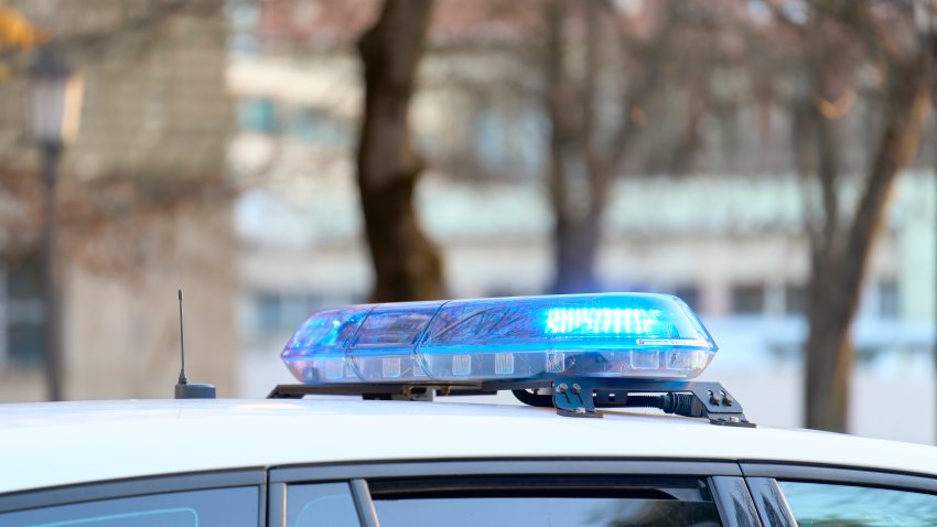 a close-up view of a police vehicle with blue lights patrolling near a public park with the windows and doors closed