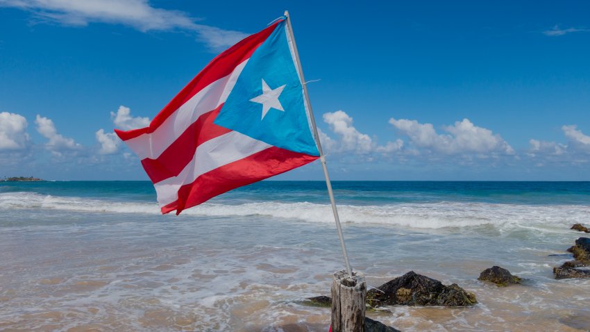 A national flag flies over beautiful sunny day on a San Juan beach in January making for an excellent escape from the winter weather in New England.