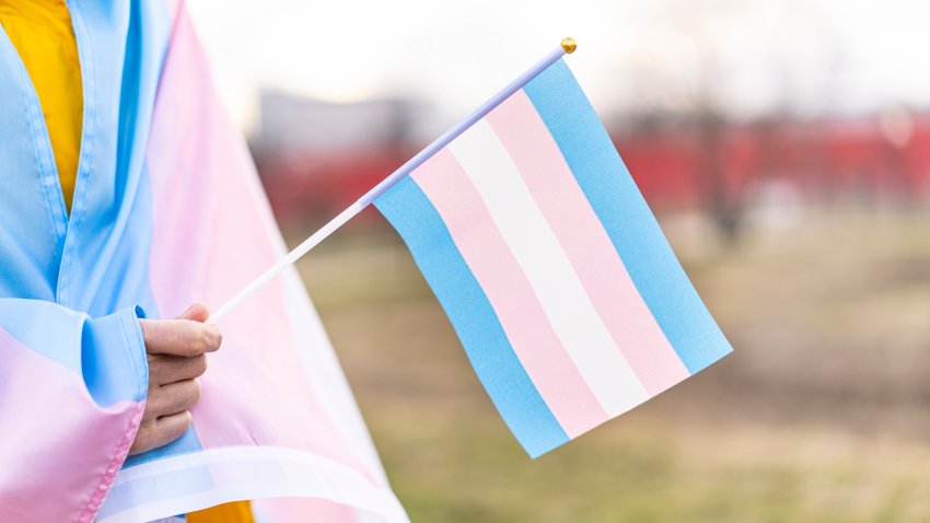 Transgender  covered with the transgender flag and holding a flag in the hand for defending her rights