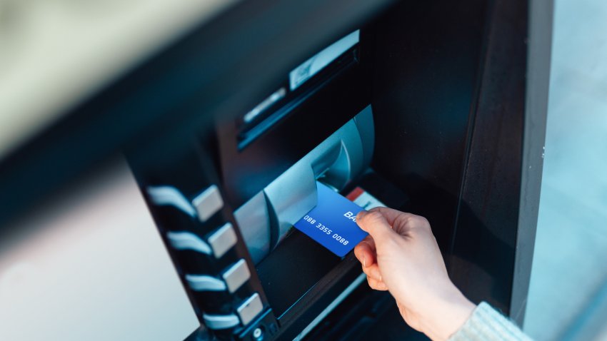 Young woman at the automatic cash machine (ATM) on city street. Auto financial service. Personal banking.