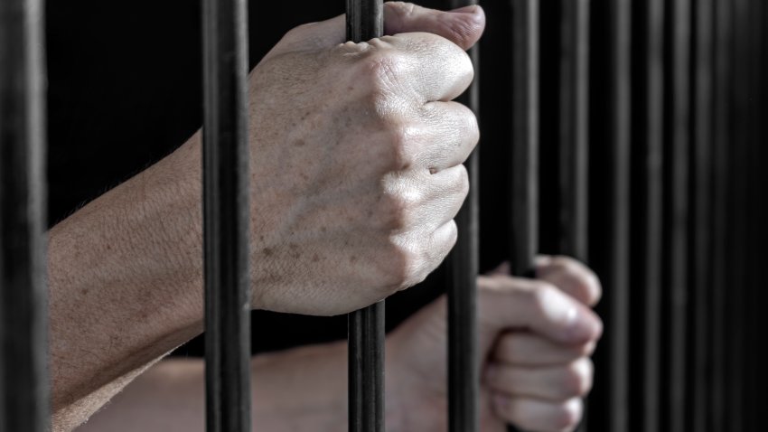 Prisoner’s hands gripping the bars of a cell in jail. Serving of prison sentences for committing crimes.