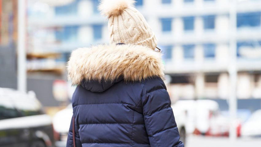 rear view of an unrecognisable lone person in a jacket and winter hat in the street.