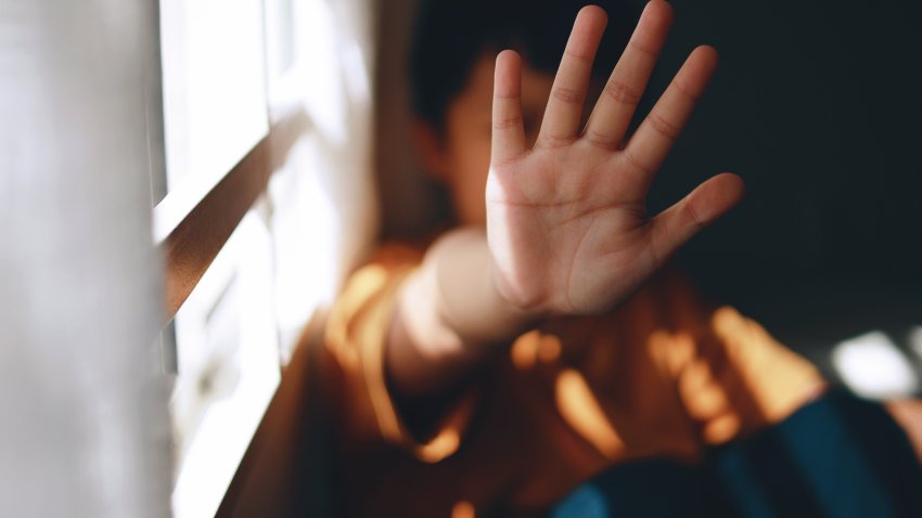 A young boy is screaming and holding his palm open in a stop gesture to counteract bullying