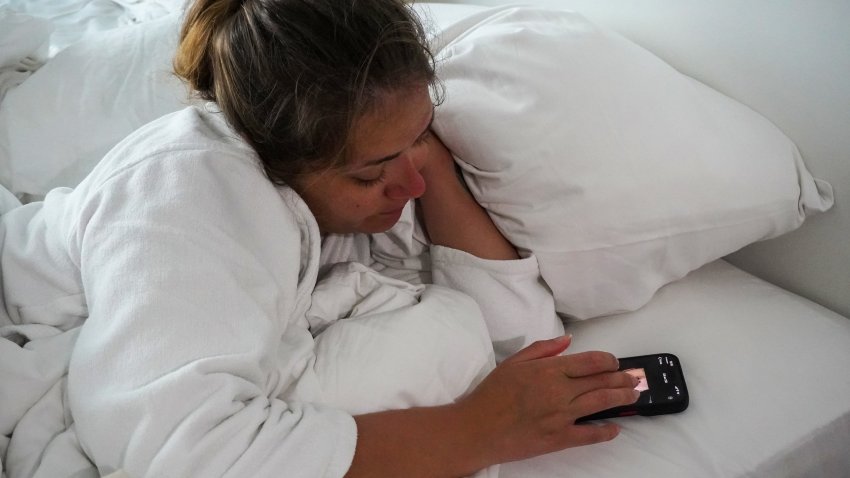 Young woman in bed looking at the phone,
