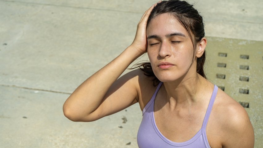 Tired athlete woman cooling down and holding her head after training on a hot summer day